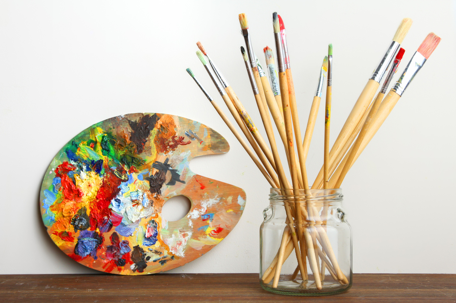 Paint brushes stand in a glass jar